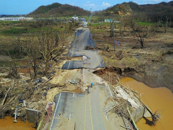 A man rides his bicycle through a damaged road in Toa Alta, west of San Juan, Puerto Rico, on September 24, 2017 following the passage of Hurricane Maria. / AFP PHOTO / Ricardo ARDUENGO (Photo credit should read RICARDO ARDUENGO/AFP/Getty Images)